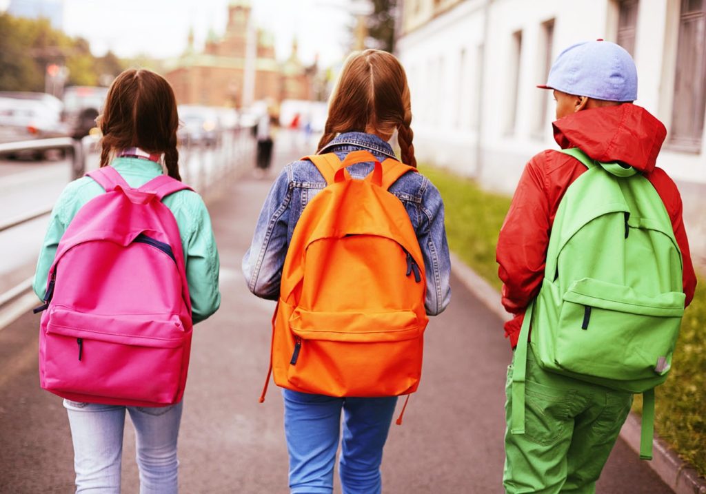 tr6es crianças com mochilas coloridas nas costas