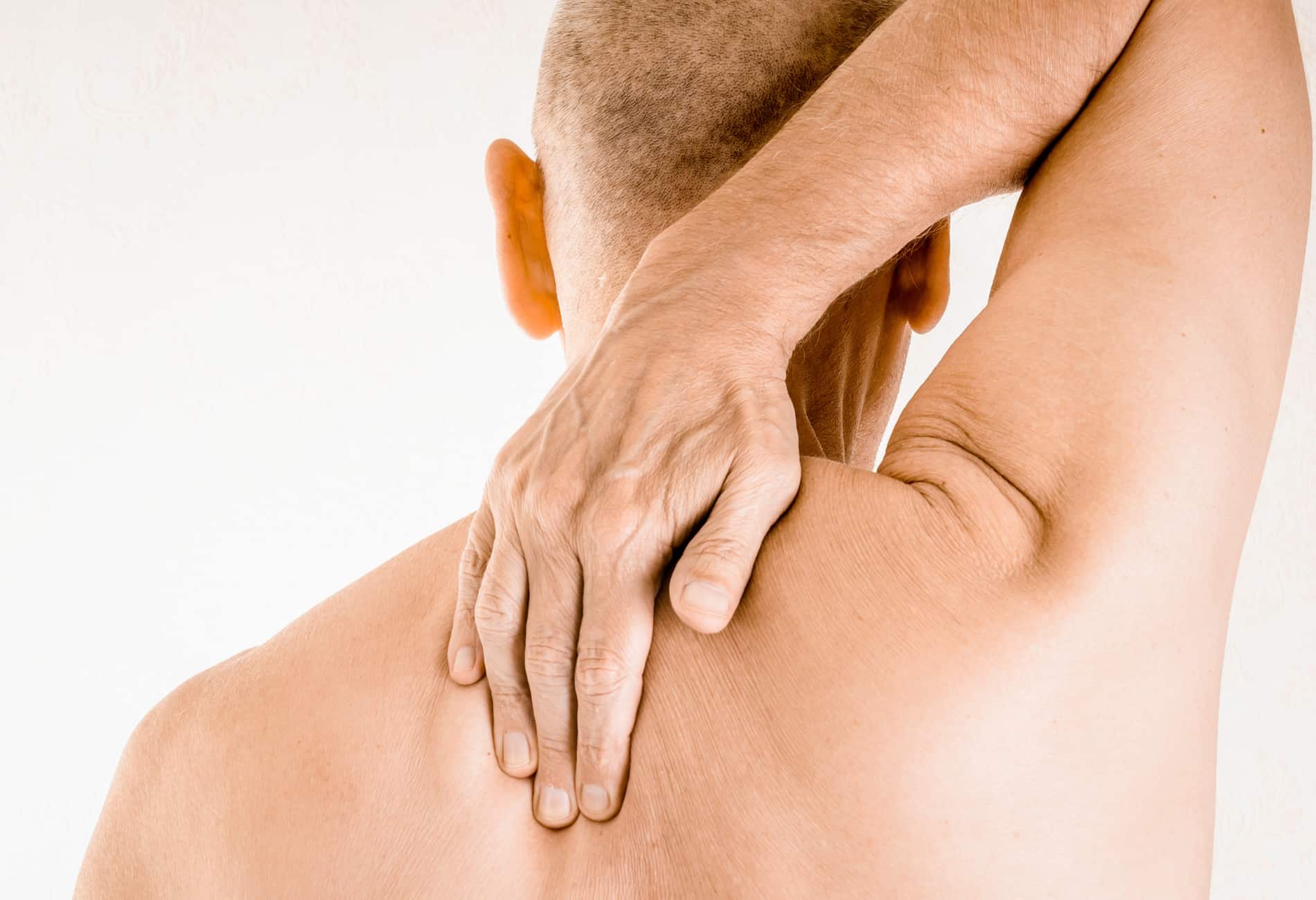 Homem com a mão no ombro e pescoço, indicando dor ou rigidez muscular. A imagem ilustra um sintoma comum de hérnia de disco cervical, que causa dor irradiada para os ombros e braços.
