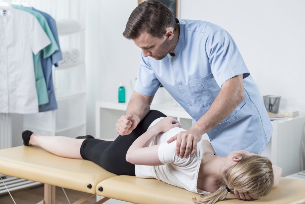 mulher em consultório com especialista tratando da coluna vertebral