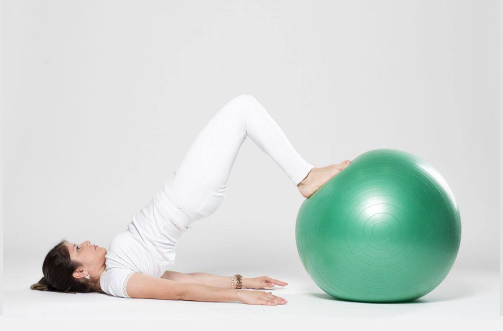 mulher fazendo exercicio com bola de pilates para aliviar a hernia de disco