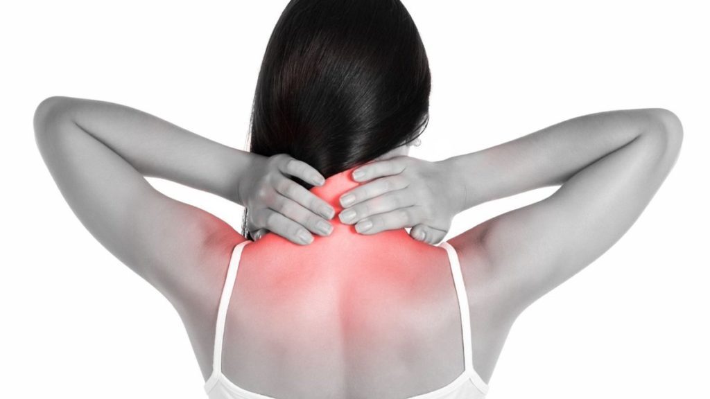 mulher de costas com as mãos sobre o pescoço dolorido por espondilose cervical