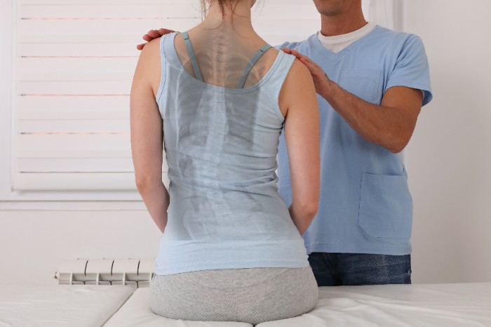 paciente com escoliose idiopática sendo avaliada por um fisioterapeuta