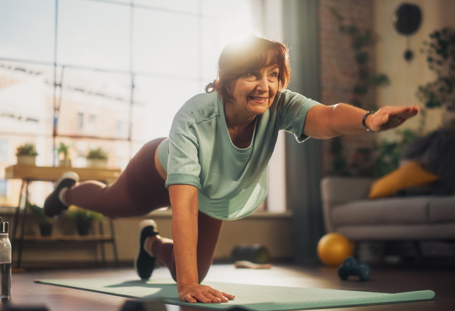 Mulher idosa realizando exercícios de fortalecimento em casa, prática recomendada para estabilizar a coluna e prevenir novos episódios de dor lombar L4 L5.