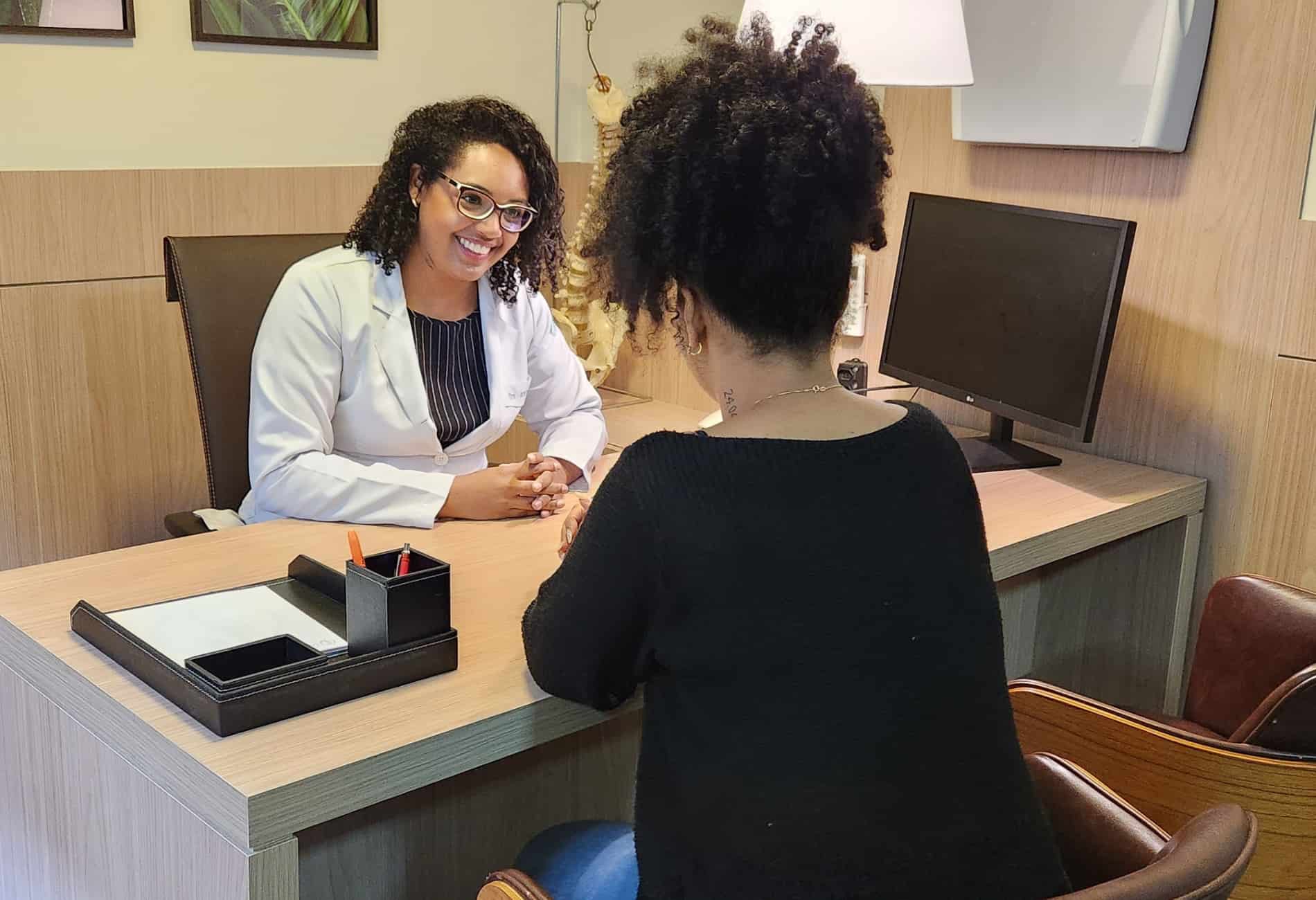 Especialista sorrindo durante consulta com paciente para iniciar o tratamento para dor na coluna torácica.